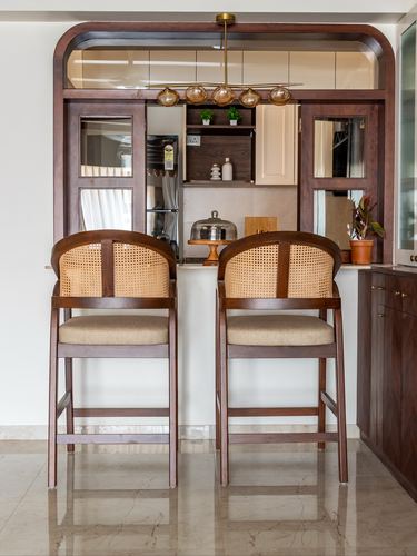 Arched wooden kitchen frame with cane-backed bar stools and brass cluster pendant light