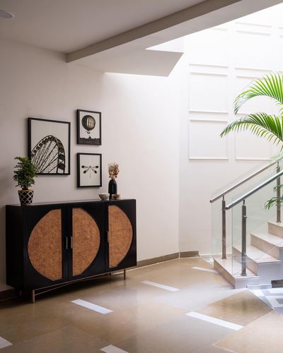 Foyer with black cane-front sideboard, framed art, and a staircase lit by a skylight