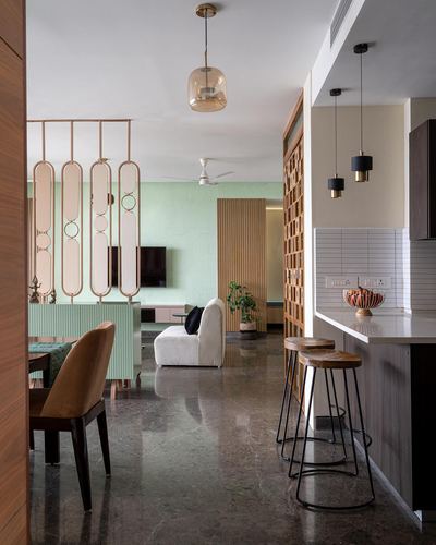 Open living and kitchen area with mint wall, mirrored screen divider, and jaali partition