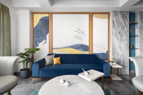 Navy velvet sofa beneath a framed crane triptych mural in a marble-accented living room