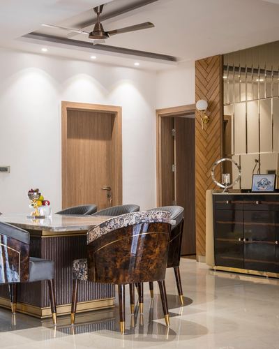 Dining area with marble-top table, burl-wood chairs, and mirrored gold sideboard in a Gurgaon home