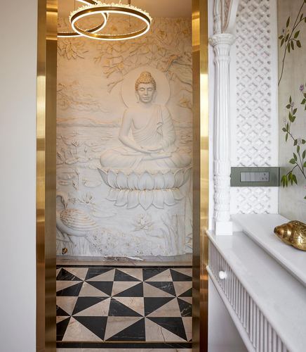 Foyer with brass-framed doorway revealing a carved Buddha mural above a geometric marble floor