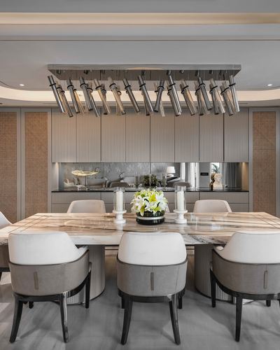 Formal dining room with marble table, grey chairs and linear tubular chandelier overhead