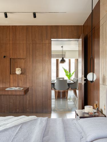 Wood-panelled bedroom with niche shelf, open door revealing dining area beyond