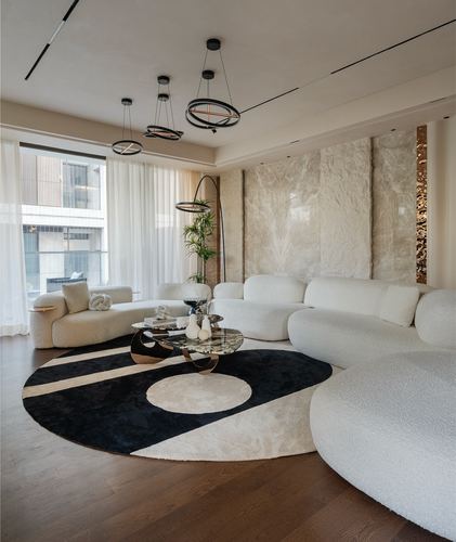 Curved white boucle sofa around round black and cream rug in bright living room