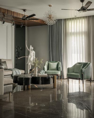 Living room with sage velvet armchairs, black nesting tables, marble floor and sculpture niche