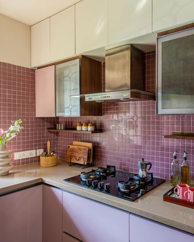 Pink tiled kitchen corner with stainless steel chimney hood over black gas hob