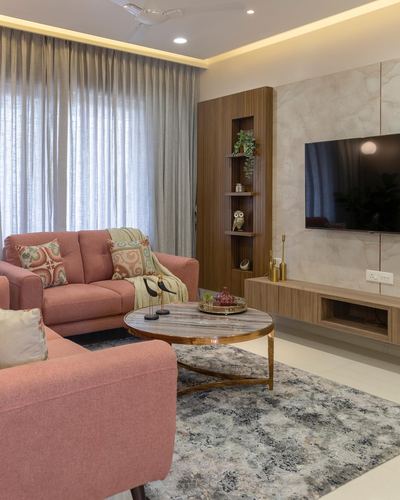 Living room with pink sofas, round marble coffee table, and marble tv wall with wooden fluted display niche
