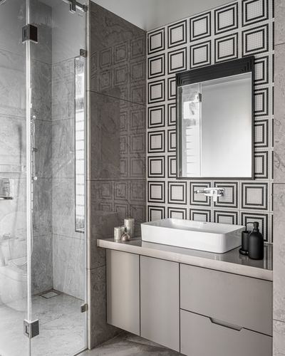 Grey stone bathroom with patterned mosaic accent wall, framed mirror, and rectangular vessel sink