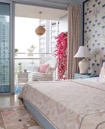 Bedroom with floral wallpaper, blue nightstand, patterned bedspread and balcony framed by pink bougainvillea