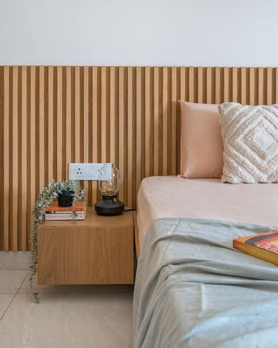 Bedroom corner with fluted wood slat wall, floating nightstand, and peach-toned bedding