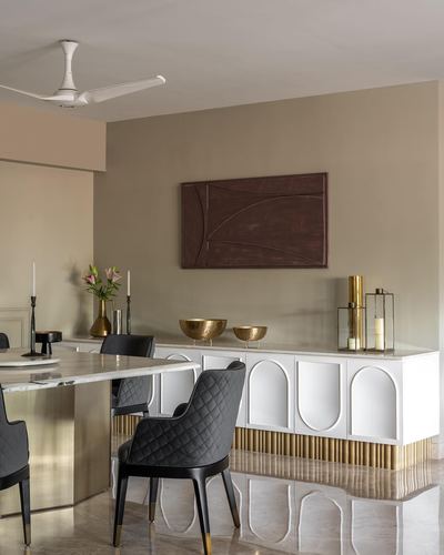 Dining room with marble table, black quilted chairs, and white arched sideboard against olive wall
