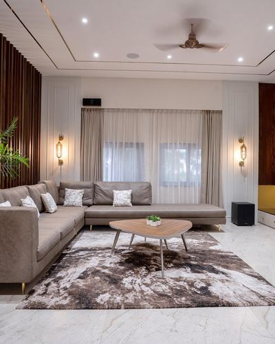 Neutral-toned living room with L-shaped sofa, wood-slat wall, sheer curtains and patterned area rug