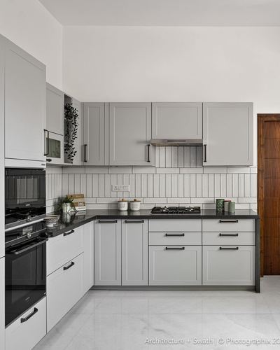 L-shaped grey shaker kitchen with black countertop and fluted tile backsplash
