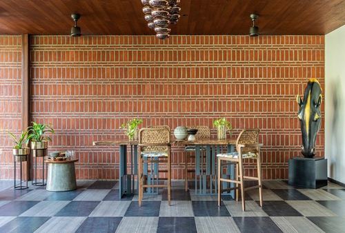 Dining area with brick wall, cane chairs, stone-top table and checkerboard floor