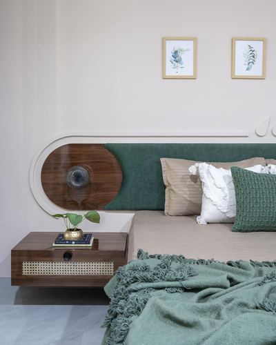 Curved walnut and green upholstered headboard beside a floating cane-front nightstand in a bedroom