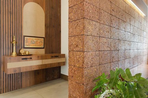 Fluted wood wall with arched niche, brass diya and floating console beside a textured stone wall corner