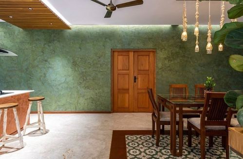 Dining area with green textured wall, wooden double door, and amber pendant lights