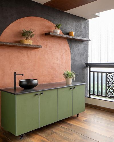 Green vanity with black bowl sink set against a terracotta arch on a charcoal textured wall