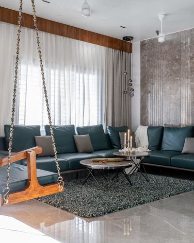 Living room with teal leather sectional, wooden swing on brass chains, and fluted stone accent wall