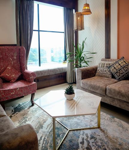 Living room with red patterned wingback chair, marble coffee table, and window seat beneath a grid window