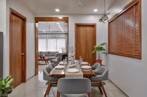 Dining room with wooden table set for six, wood-framed blinds, view into living room beyond