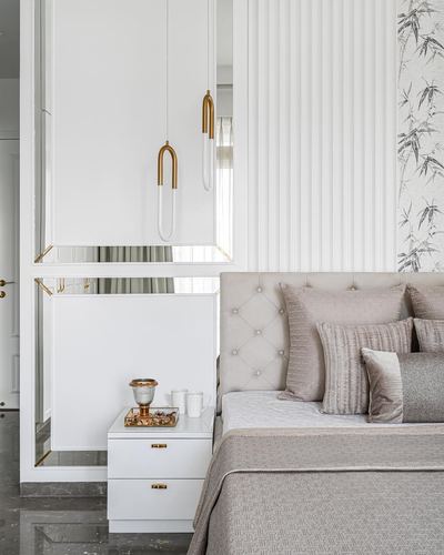 Neutral bedroom with tufted headboard, brass pendant lights, and mirrored nightstand panel