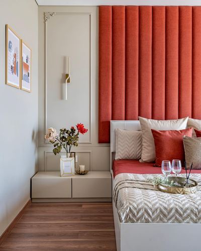 Bedroom corner with orange channel-tufted headboard wall, beige moulding niche, and wood flooring