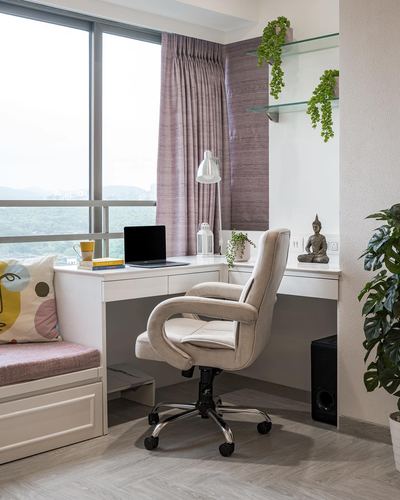 Corner study nook with white desk, cream office chair, window seat, and city view through glass window