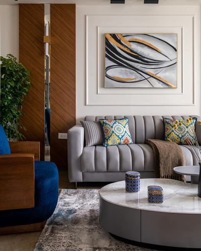 Living room with grey channel-tufted sofa, round marble coffee table, and abstract art above