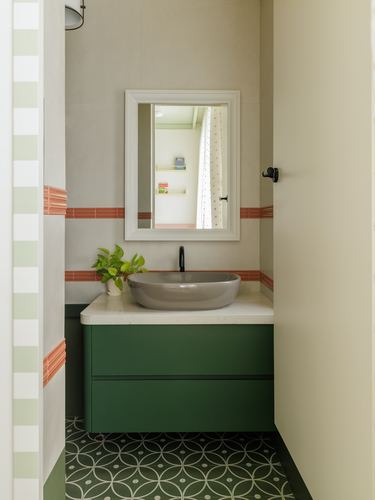 Bathroom with green vanity, oval basin, terracotta tile trim, patterned floor and mirror