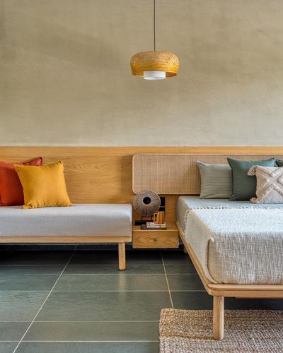 Two beds meet at a corner nightstand with cane headboard and pendant light in warm bedroom