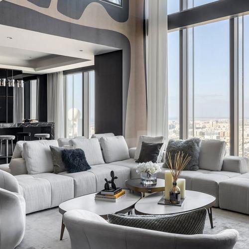 Grey sectional sofa and nesting coffee tables in a high-rise living room with floor-to-ceiling city view