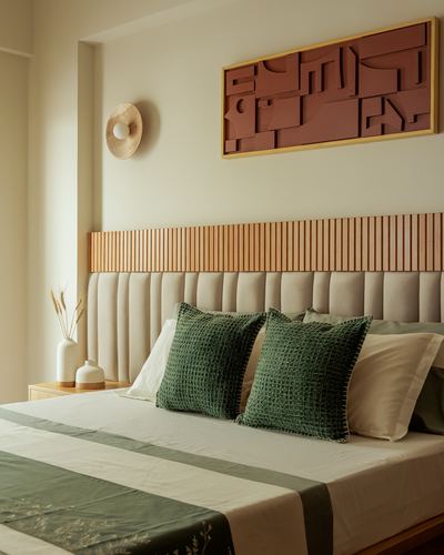 Bed with beige tufted headboard, fluted wood strip, terracotta relief art, and green pillows