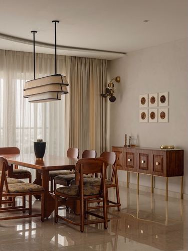 Dining room with wood table, floral chairs, tiered pendant lights, and brass-legged sideboard