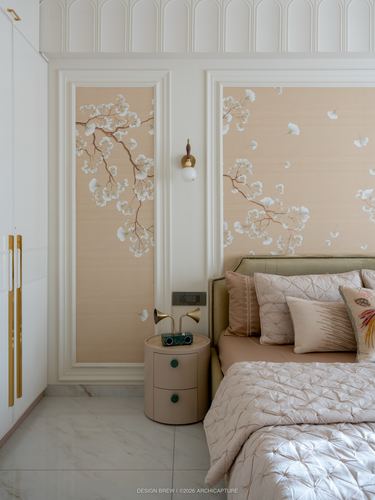 Blush bedroom with floral wallpaper panels, brass sconce, and round pink nightstand beside upholstered bed