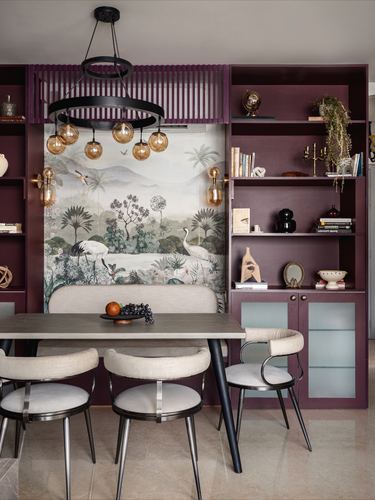 Dining nook with maroon shelving, botanical crane mural, round table and cane-back chairs