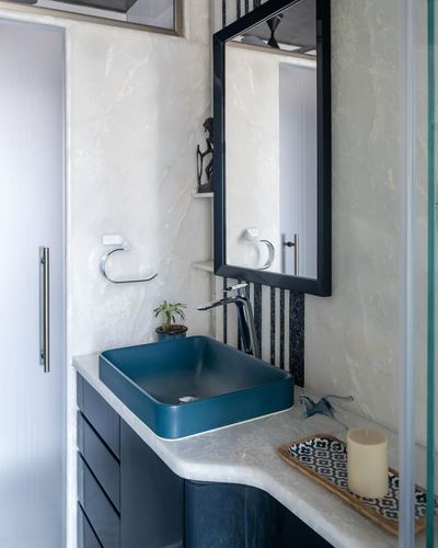 Bathroom vanity corner with teal vessel sink, marble counter, and black-framed mirror
