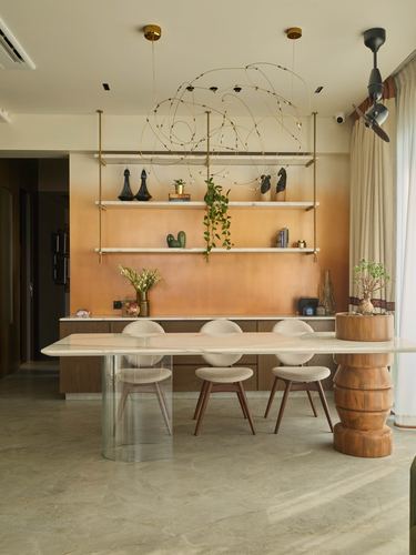 Dining area with marble table, cane-back chairs, and suspended shelving against an ombre orange wall