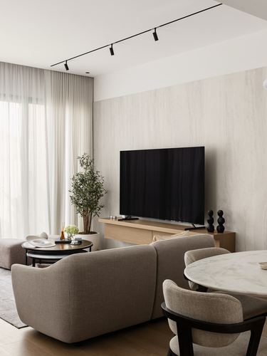 Neutral living room with stone accent wall, wall-mounted TV, taupe sofa and marble dining table edge