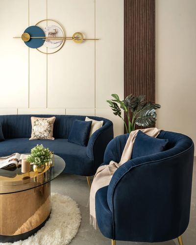 Navy velvet curved sofa and armchair around a brass and glass coffee table in a cream-paneled living room
