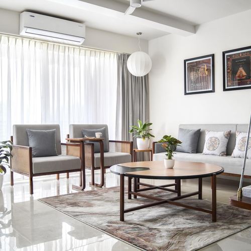 Living room with cane armchairs, grey sofa, round wood coffee table and sheer curtains