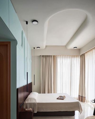 Bedroom with sculpted arched ceiling, mint textured wall panel, dark wood bed and sheer curtains