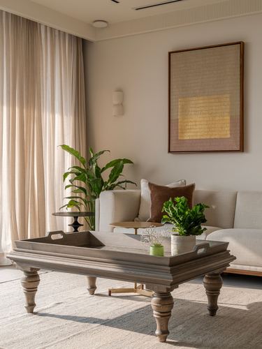 Neutral living room with turned-leg coffee table, beige sofa, and textured framed art