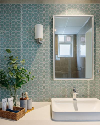 Bathroom vanity with teal geometric tile wall, mirror reflecting window, white vessel sink