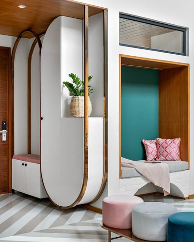 Foyer with oval brass-trimmed wardrobe beside a teal built-in window seat nook