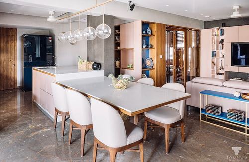 Open-plan kitchen and living space with dining table under glass pendant cluster and pink cabinetry