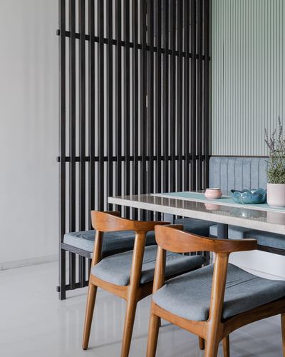 Dining nook with wooden chairs, stone-top table, and black slatted screen partition