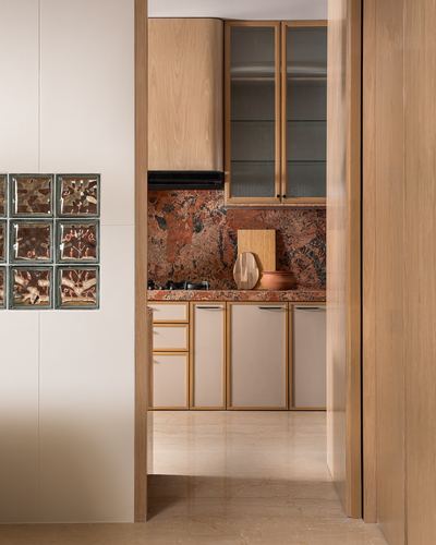 Kitchen glimpsed through a doorway with patterned stone backsplash and glass block wall beside it