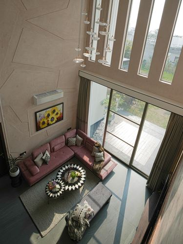 Overhead view of double-height living room with pink sectional and cluster pendant lights